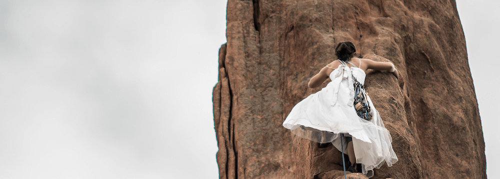Lady in dress climbing up cliff