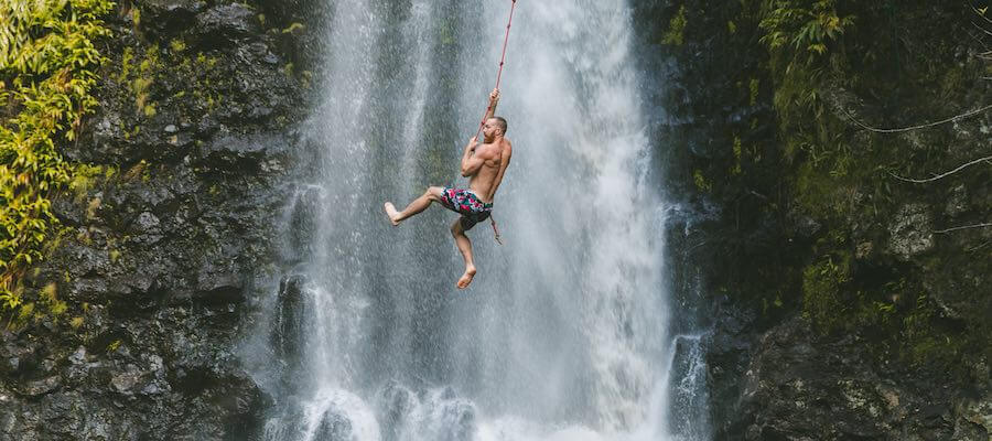 Man swinging across waterfall