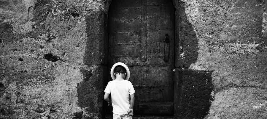 Boy standing in front of old locked door